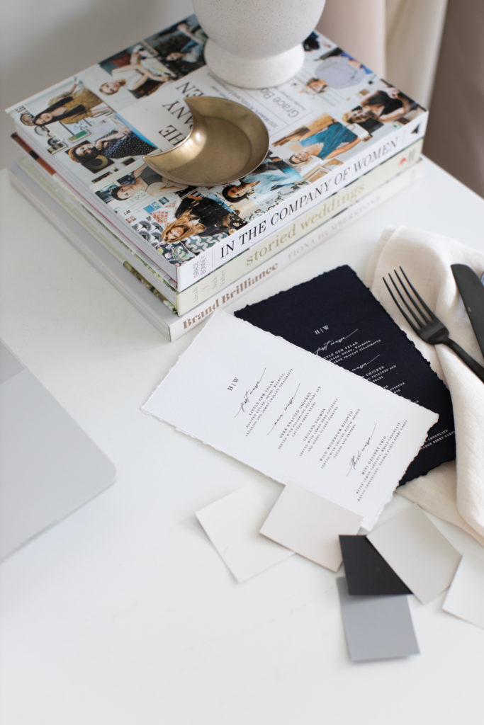 a wedding planners desk with wedding books and invitations