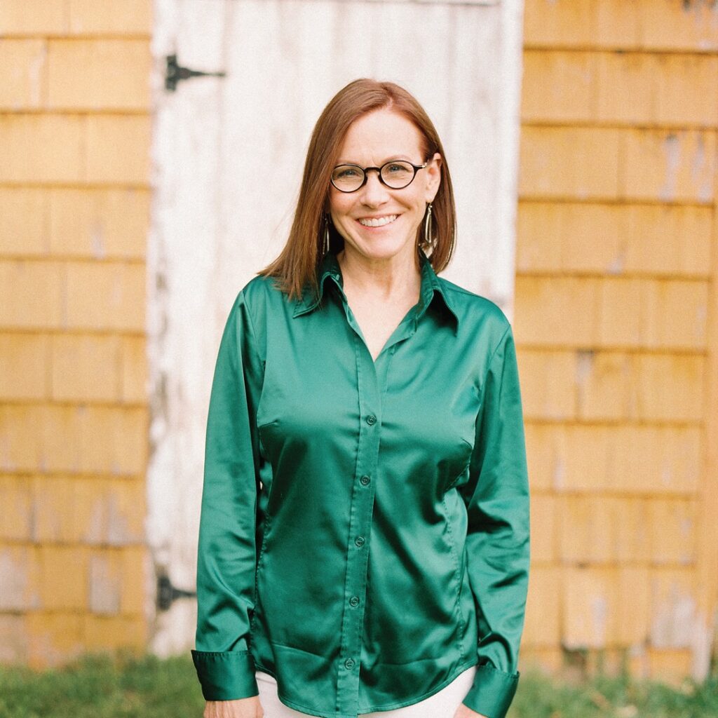 A woman in a green shirt standing in front of a barn, named Dana Bartone.