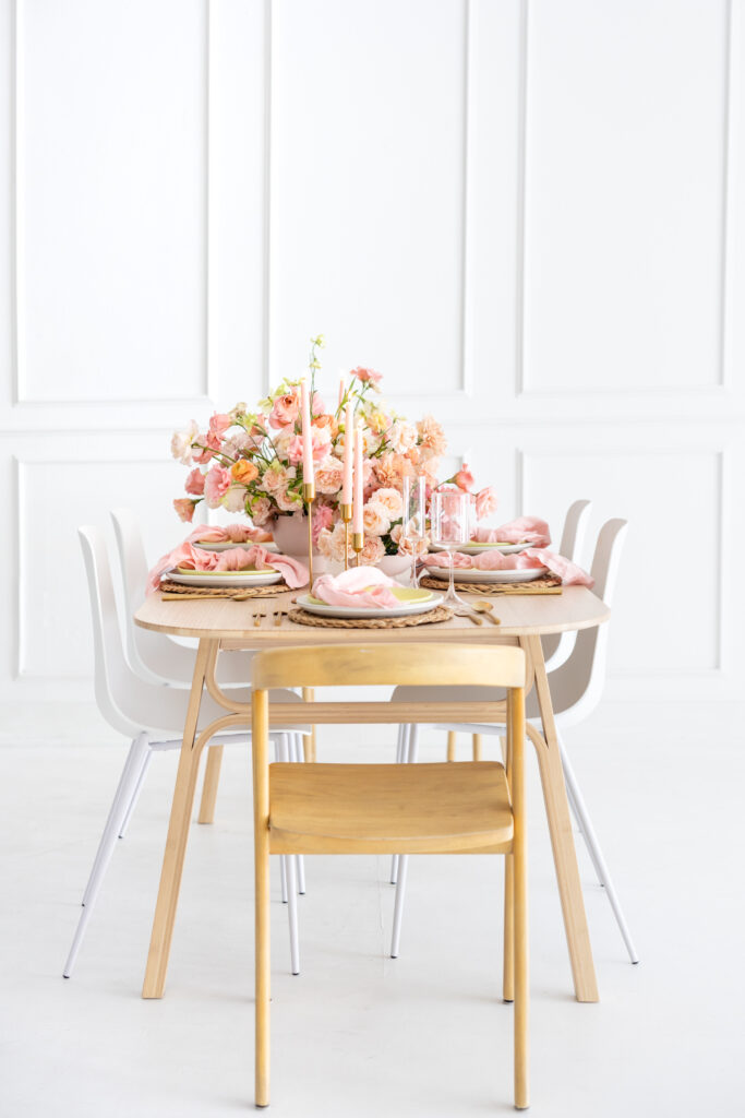 A white table with pink flowers and white chairs, perfect for wedding business packages.