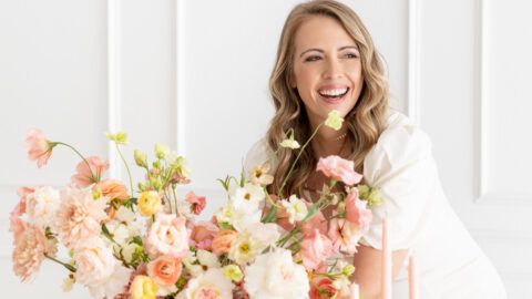 A woman holding a table full of pink and gold flowers for your wedding business.