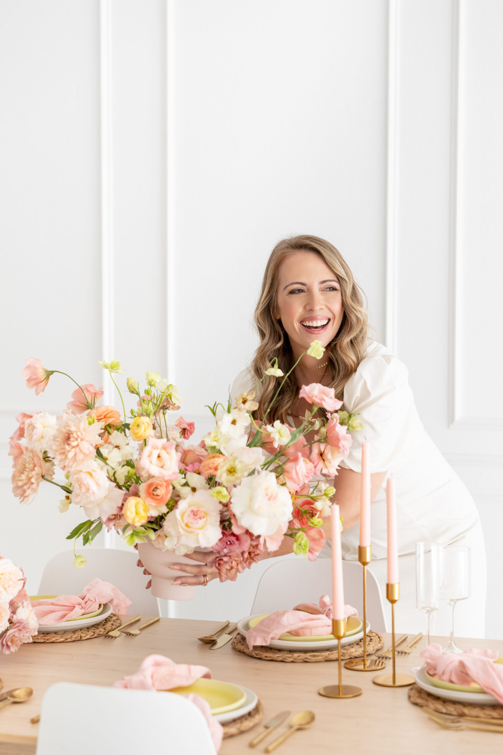 A woman holding a table full of pink and gold flowers for your wedding business.