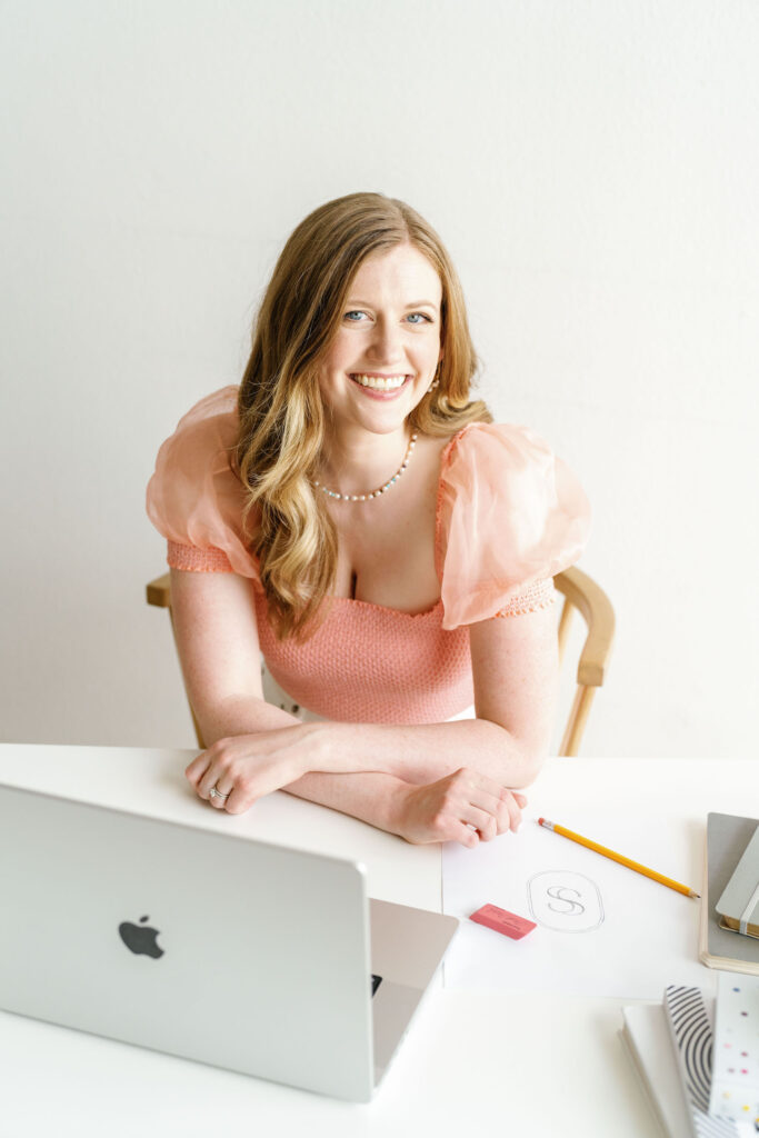 Alex Collier, a woman, sitting at a desk with a laptop.