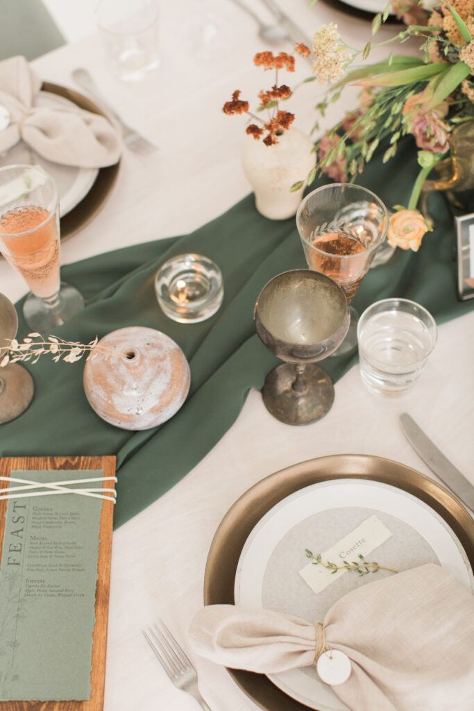 A table setting with a green runner and place settings for the wedding planner process.