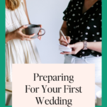 Two women, one holding a coffee cup and the other with a notebook, smiling and standing by a wall with a promotional poster for preparing for your first wedding.