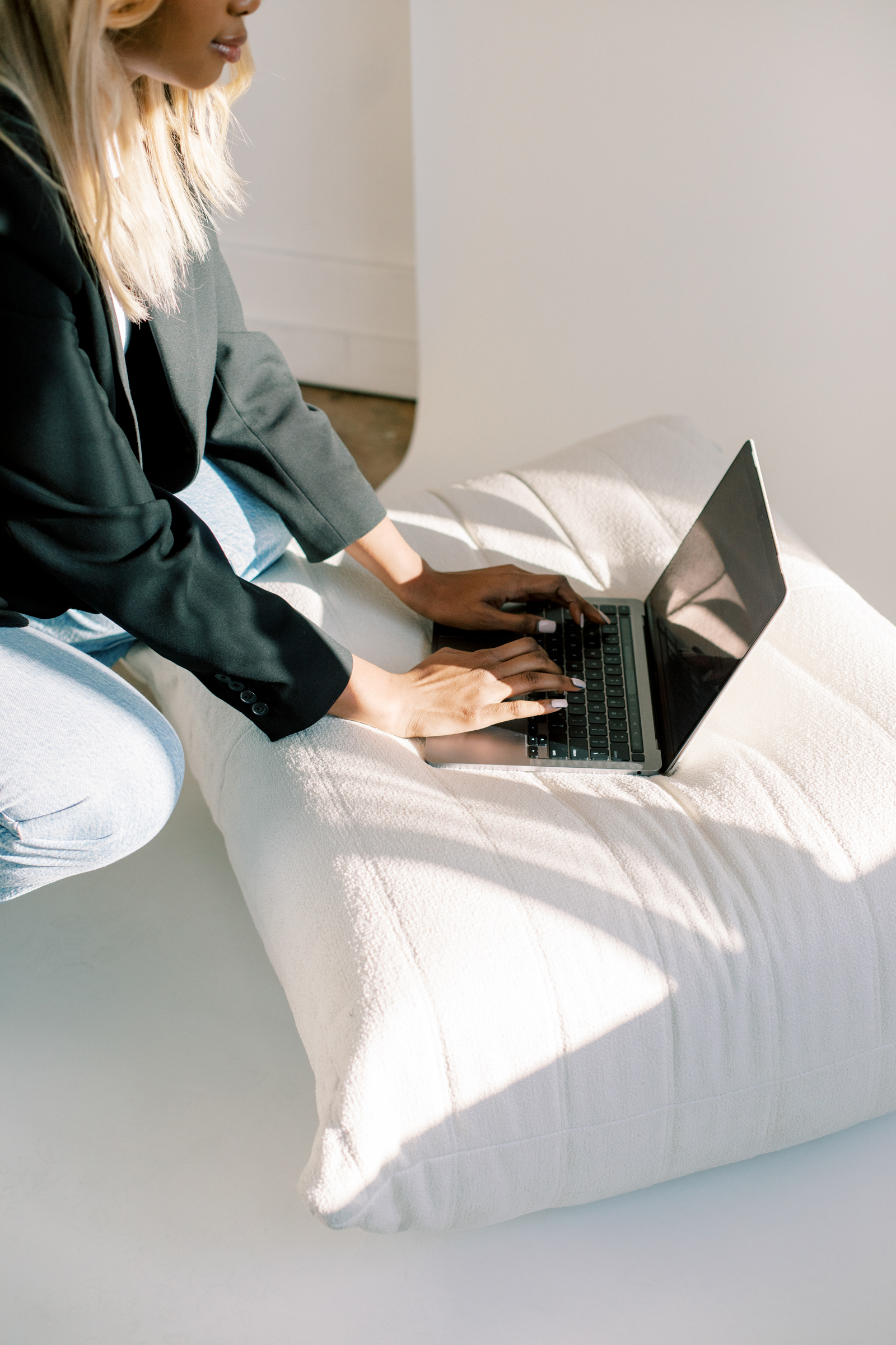 A person using a laptop on a large white cushion, likely crafting the perfect lead magnet.