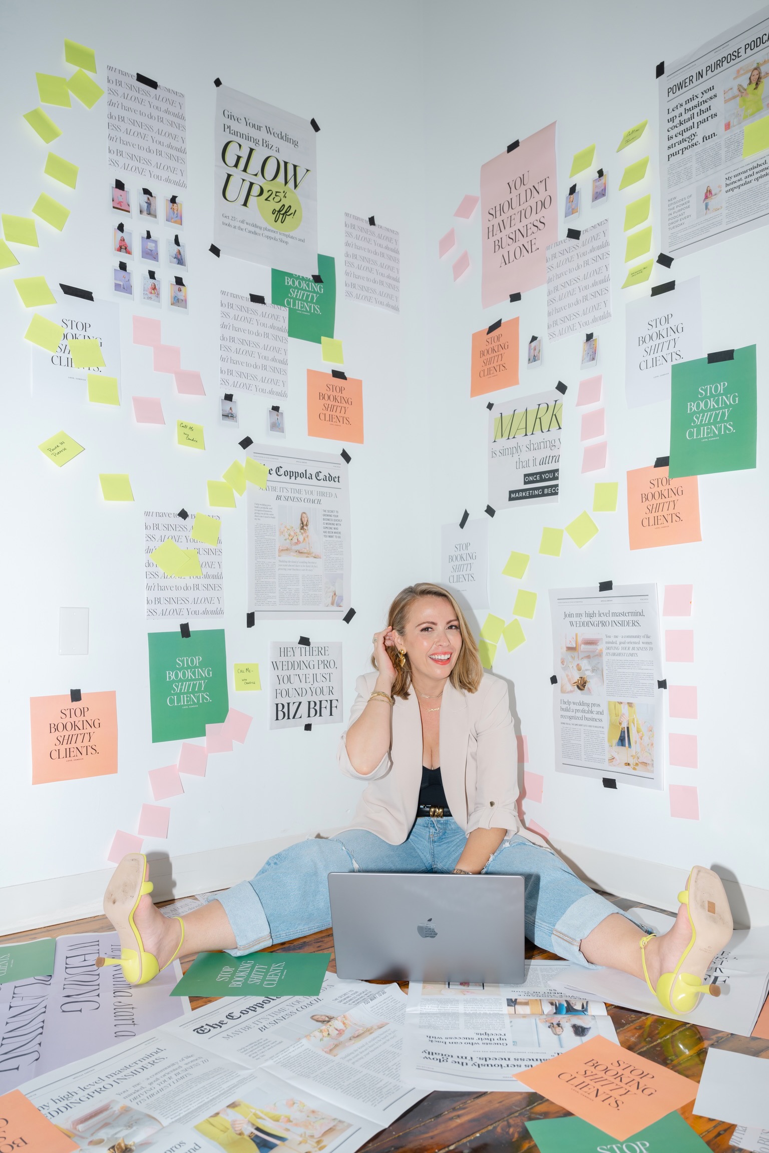 A person sits on the floor in a room adorned with many motivational posters and sticky notes, absorbed in their laptop. The vibrant space is filled with colorful posters and newspaper clippings, all inspiring their journey toward six-figure marketing success.